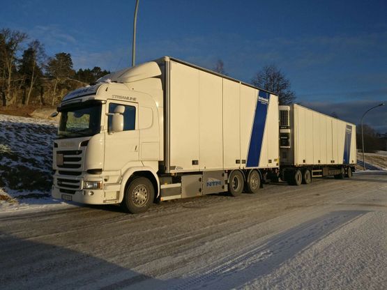 Vit lastbil med kylsläp på vinterväg i dagsljus